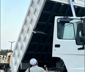 Cliente inspeciona camião basculante HOWO 371HP 6×4 recondicionado com caixa elevada no pátio da fábrica